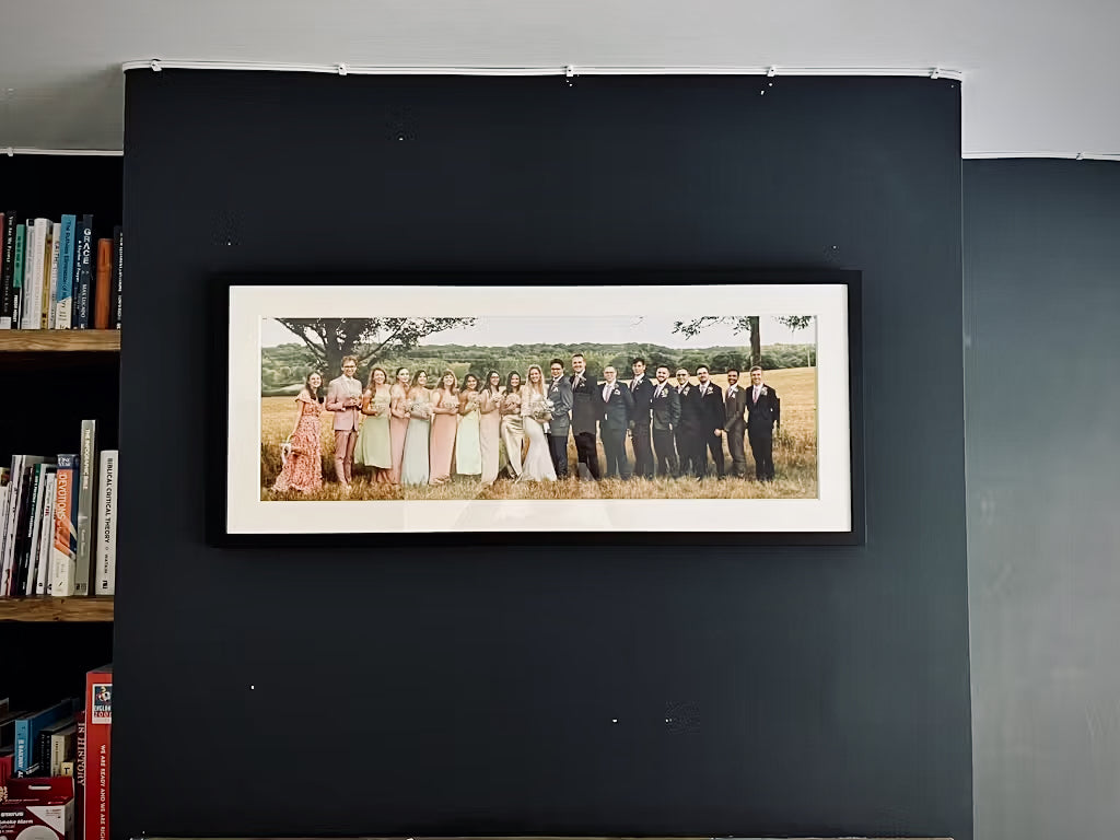 a customers image of their wedding photo framed and hanging on the wall next to bookshelf