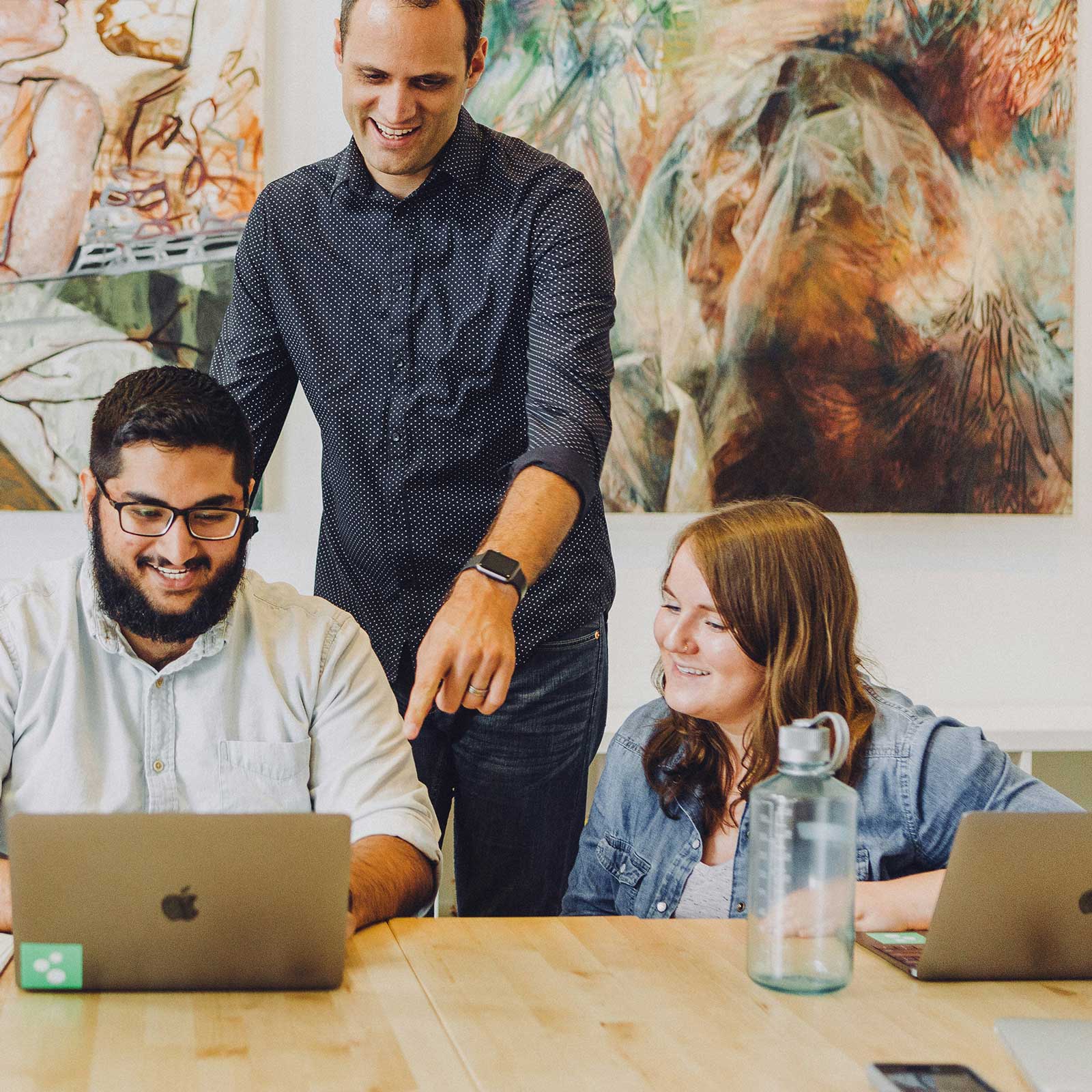 happy office workers next to large canvas