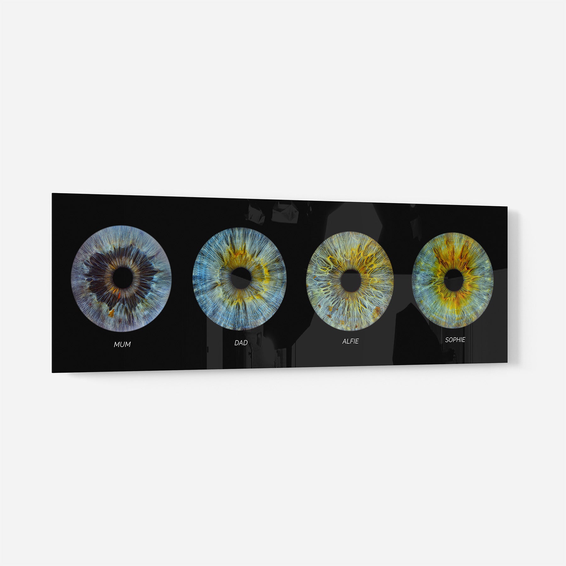 Acrylic print with four eye designs labeled 'Mum', 'Dad', 'Alfie', and 'Sophie' on a black background.