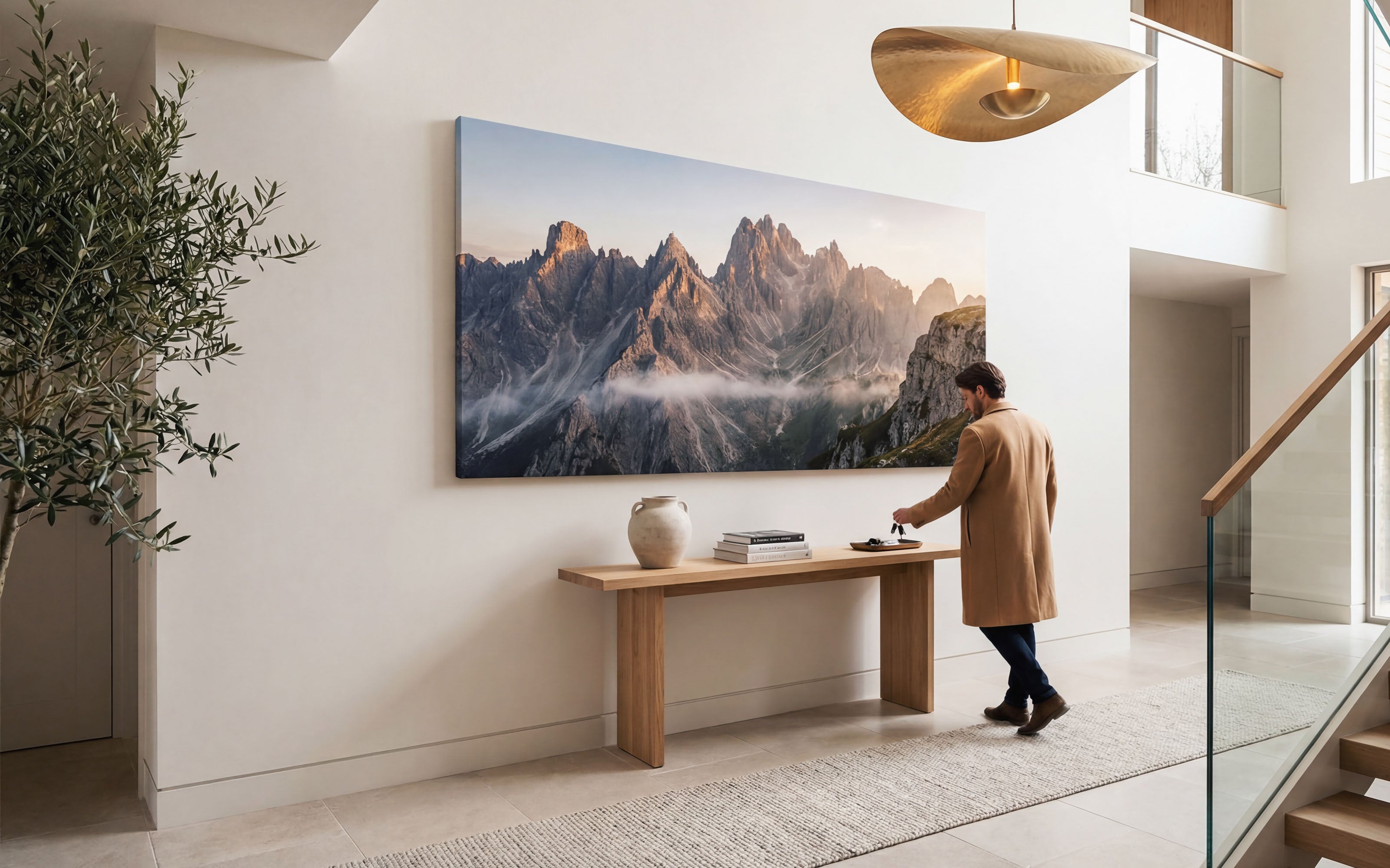 Person standing in a modern home entrance hall with a large mountain panoramic canvas print on the wall.