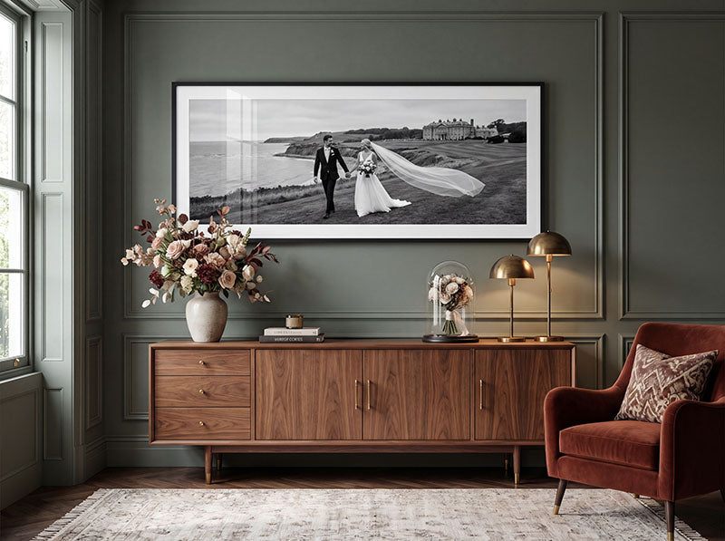 Black framed panoramic wedding photograph above a wooden sideboard